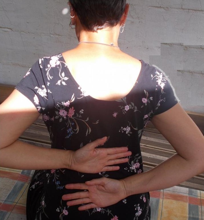 Photo d'une personne de dos effectuant un geste d'auto-massage dans son dos. 